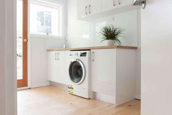 White laundry cabinetry with timber laminate benchtop